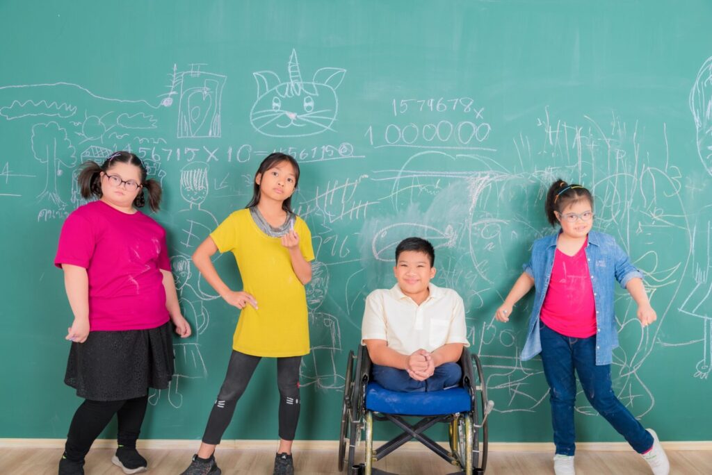 Group of young Asian disabled child student standing in front of chalkboard in element classroom, Inclusion, Support & Advocacy, Empowerment, Awareness, Dignity, Community Engagement, Ability Beyond Limits
